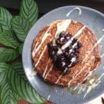 banana blueberry pancakes drizzled with tahini next to a plant