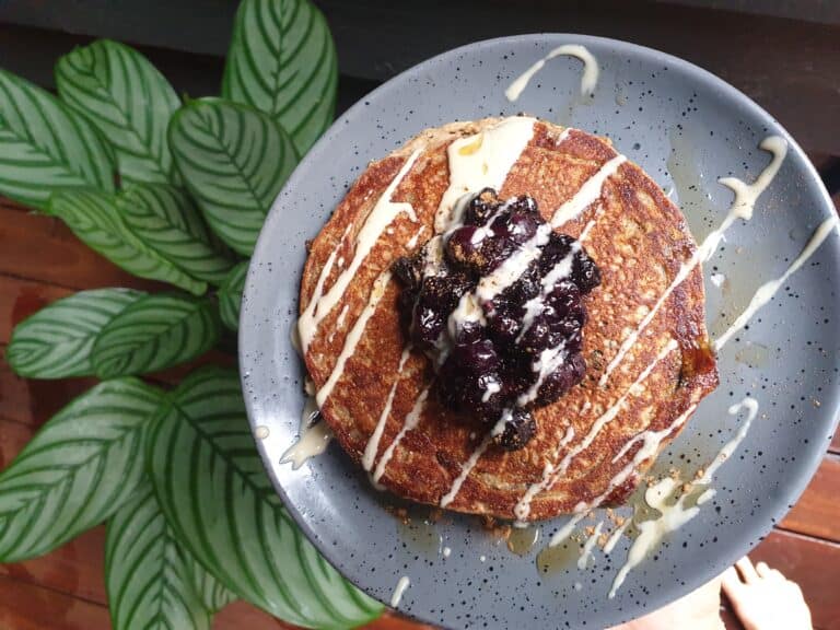 banana blueberry pancakes drizzled with tahini next to a plant