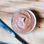 chocolate frosting in a ramekin with a knife to the side