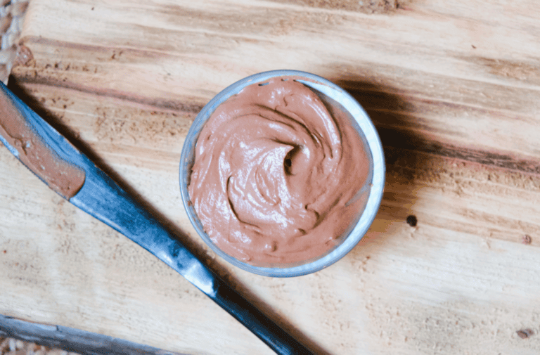 chocolate frosting in a ramekin with a knife to the side