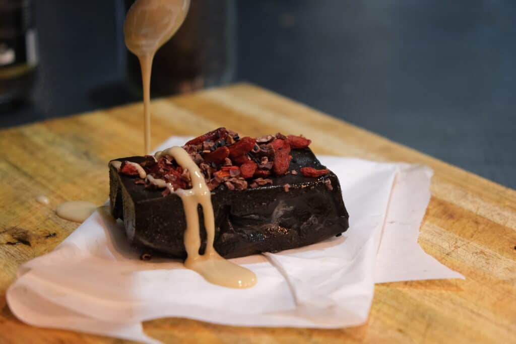 black tahini fudge with tahini being poured overtop