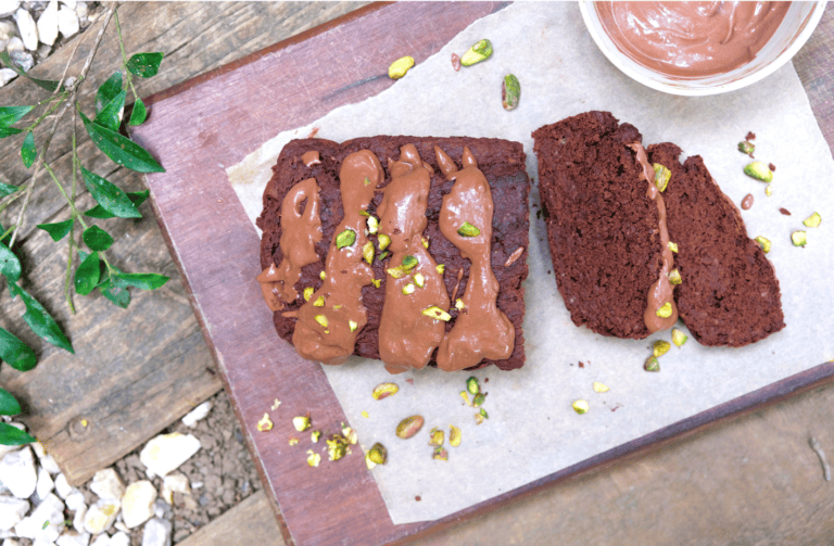 chocolate cake with chocolate frosting, pistacchios and a slice cut out