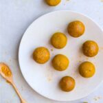 turmeric balls on a white plate with spoon of powdered turmeric