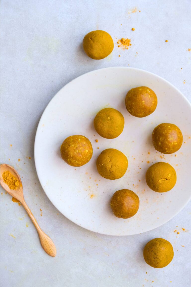 turmeric balls on a white plate with spoon of powdered turmeric